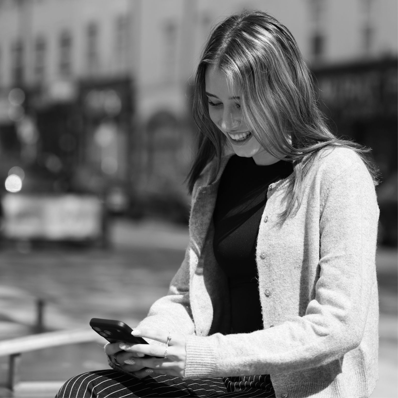 Smiling woman using mobile phone on a UK high street