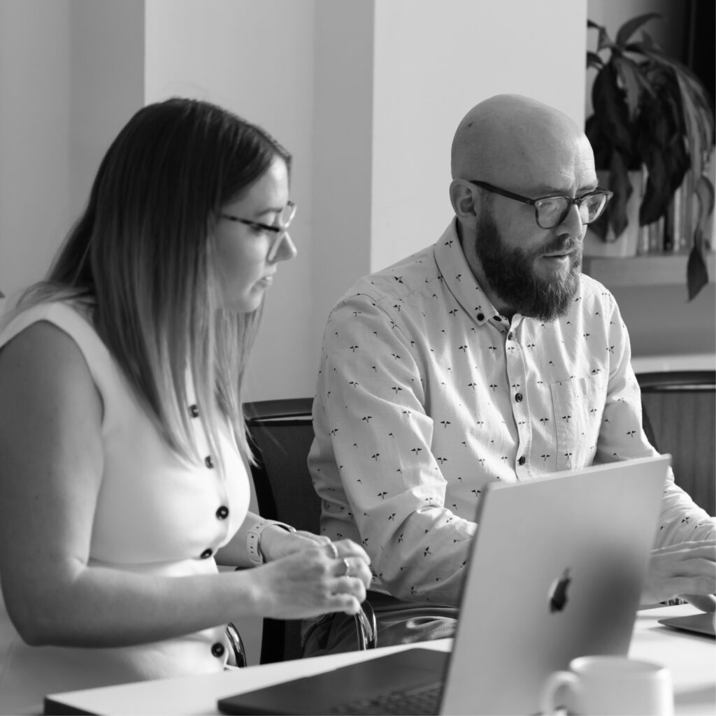 Two marketers discussing campaign plans on a laptop